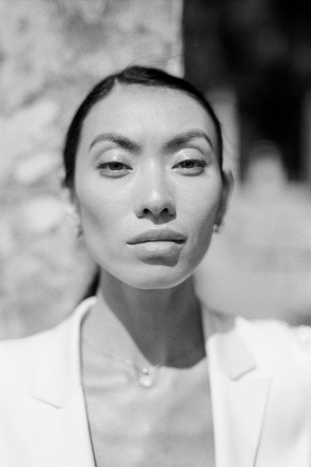 Czarno-biały portret kobiety w jasnej marynarce, patrzącej prosto w obiektyw