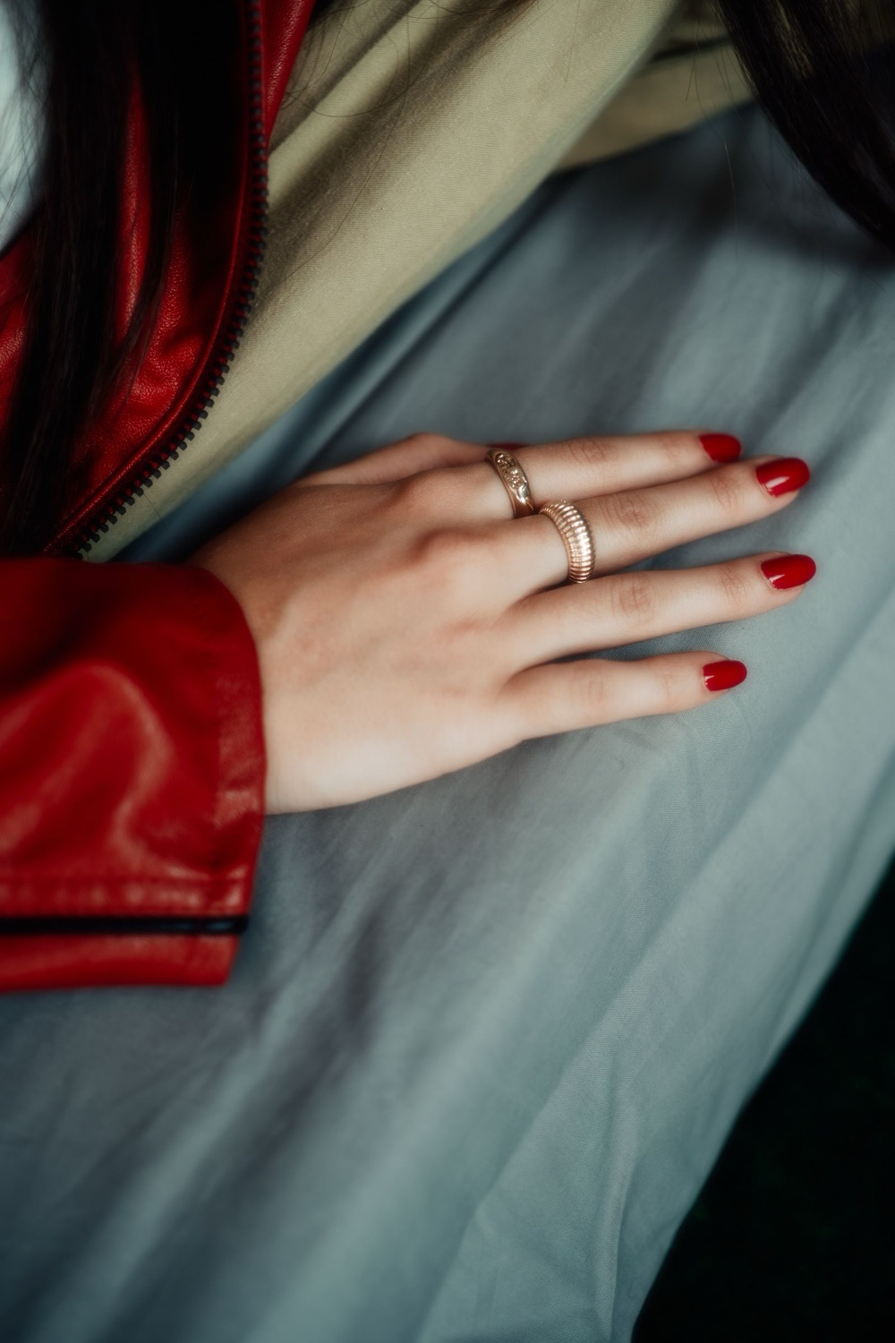 Dłoń z wiśniowym manicure i złotymi pierścionkami