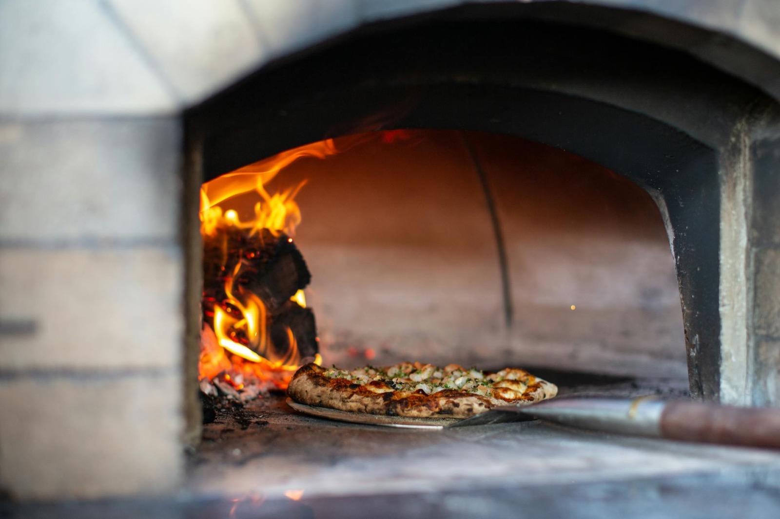 Pizza piecze się przy płonącym drewnie w kopułowym piecu