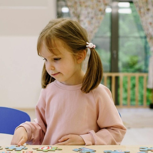 Dziewczynka układa puzzle przy stoliku